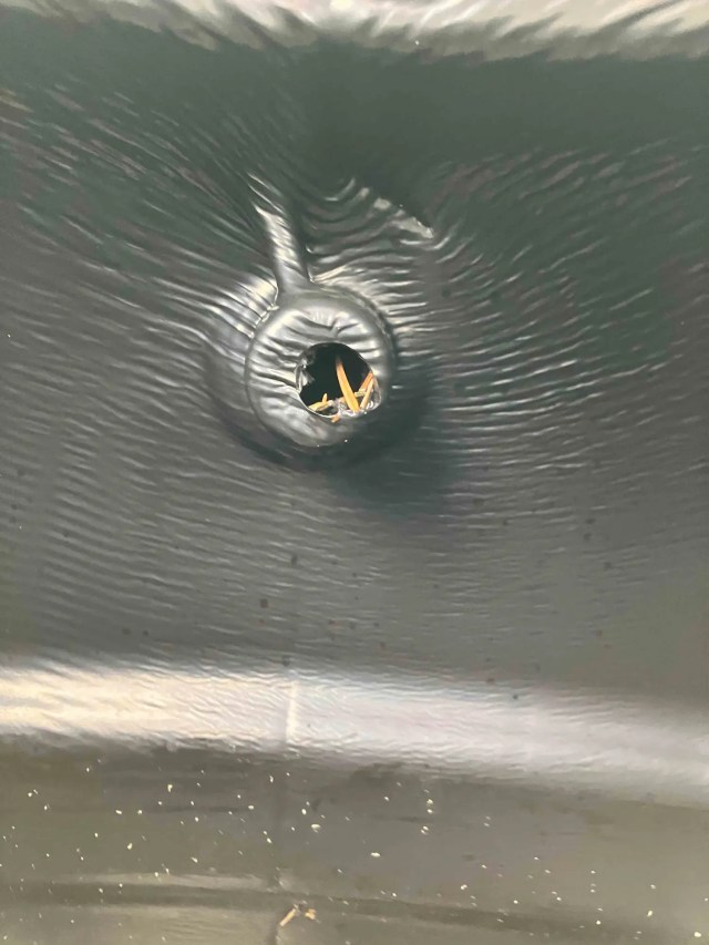 Close-up of a narrow inlet on a black plastic water butt before modification.